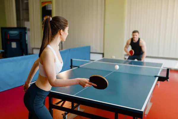 屋内で卓球をする男女 スポーツウェアのカップルはラケットを保持し ジムで卓球をします — ストック写真