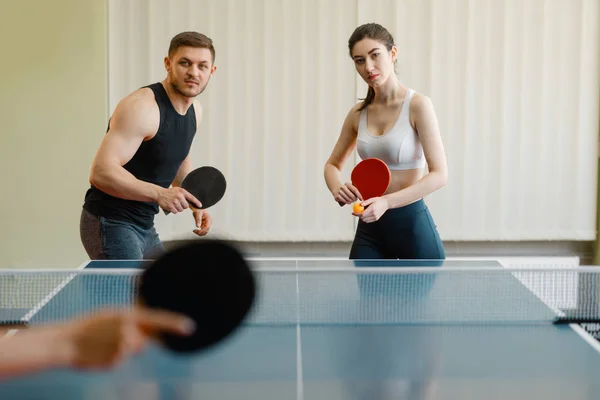 Friends playing sport game, group ping pong indoors. People in sportswear holds rackets and plays table tennis in gym