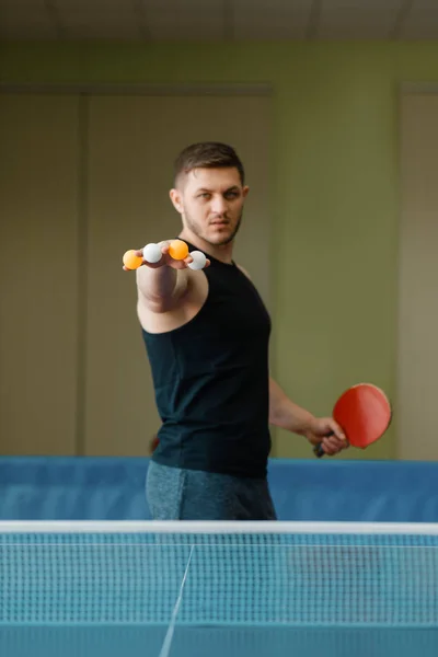 ラケットを持つ男は 指の間にピンポンボールを保持し 屋内でワークアウト スポーツウェアの男性 卓球部でのトレーニング — ストック写真