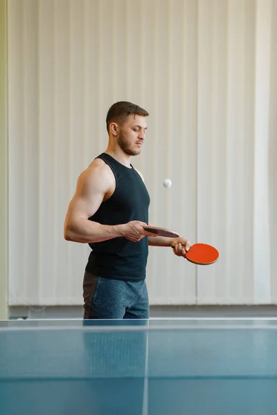 2つのラケットを持つ男は 屋内のピンポンで吹きます ネット付きテーブルでスポーツウェアを着た男性 卓球部でトレーニング — ストック写真