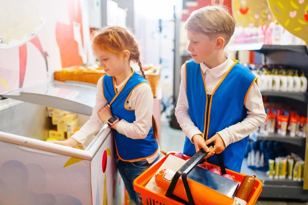 制服を着た子供たち セールスマンを演じる男の子と女の子 プレイルーム 子供たちは架空のスーパーマーケットで売り手を果たしています セールスマン職業学習 — ストック写真