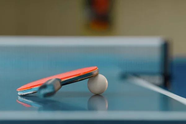 Ping pong racket and ball on game table with net, nobody, closeup view. Table-tennis club, tennis concept, ping-pong symbol