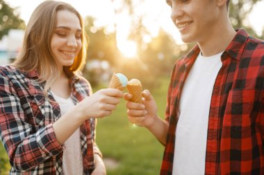 Genç aşk çifti yaz parkında birbirlerine dondurma yedirirler. Erkek arkadaş ve kız arkadaşı dondurma, romantik yürüyüş ile birlikte leisures