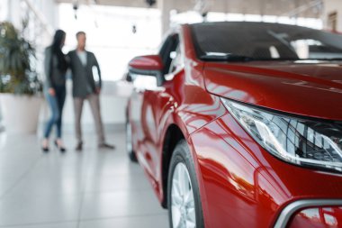 Çift showroom yeni kırmızı araba satın alıyor. Erkek ve kadın müşteriler bayilik, otomobil satışı, otomobil satın alma araç görünüyor