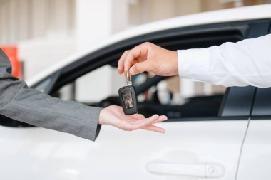 Müdür kadına showroom'daki yeni arabanın anahtarını veriyor. Bayilik, otomobil satışı kadın müşteri satın alma aracı