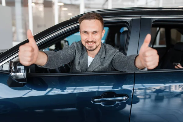 Hombre Sentado Coche Nuevo Muestra Los Pulgares Hacia Arriba Sala — Foto de Stock