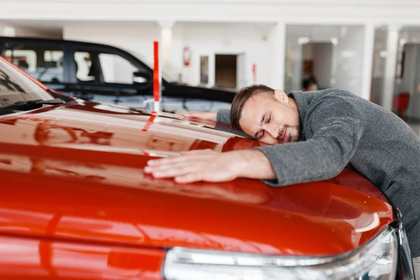 Mann Liegt Auf Der Motorhaube Eines Neuwagens Verkaufsraum Männlicher Kunde — Stockfoto