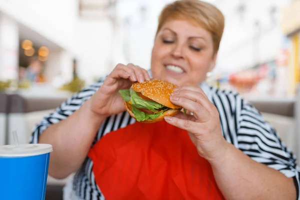 モールフードコートでファーストフードを食べる太った女性 ジャンクランチでテーブルで太りすぎの女性 — ストック写真