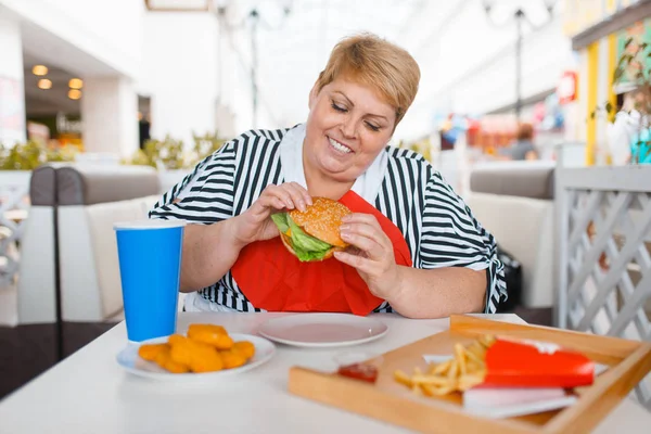 モールフードコートでファーストフードを食べる太った女性 ジャンクランチでテーブルで太りすぎの女性 — ストック写真