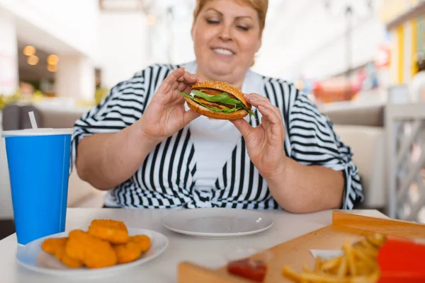 モールフードコートでファーストフードを食べる太った女性 ジャンクランチでテーブルで太りすぎの女性 — ストック写真