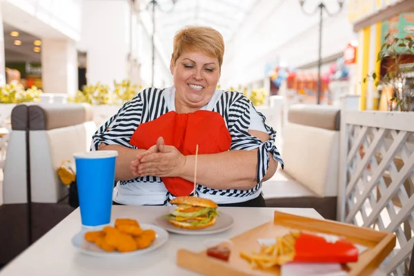 太った女性はモールフードコートでファーストフードを食べる準備をします ジャンクランチでテーブルで太りすぎの女性 — ストック写真