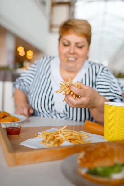 モールレストランで高カロリーの食べ物を食べる太った女性 ジャンクディナー 肥満の問題でテーブルで太りすぎの女性 — ストック写真