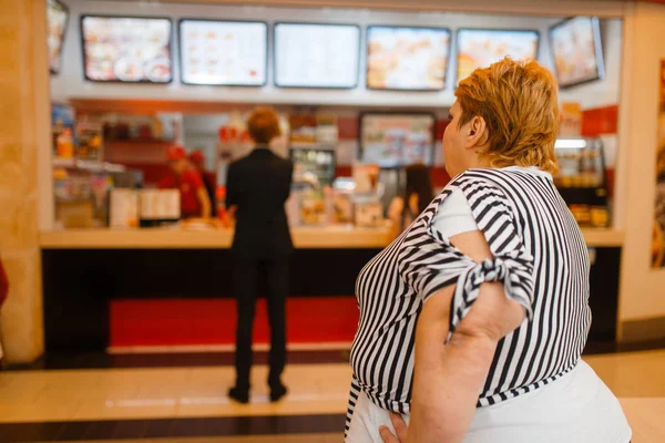 ファーストフードレストランのメニューで太った女性 太りすぎの女性はファーストフードを買う 肥満の問題 — ストック写真