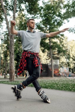 Paten kayıyor, erkek kaykaycı parkta yuvarlanıyor. Şehir pateni, açık havada aktif ekstrem spor