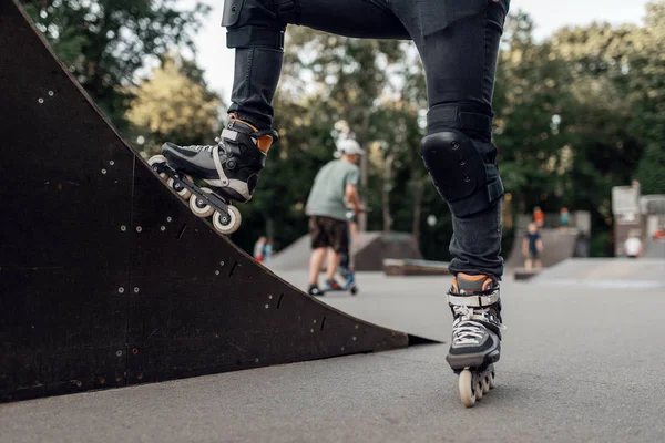 Roller skating, male skater standing on ramp in park. Urban roller-skating, active extreme sport outdoors