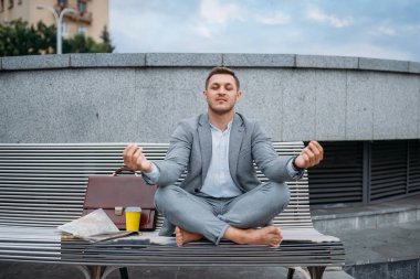 İş adamı yoga pozisyonunda şehir merkezindeki ofis binasında dinleniyor. Şehir caddesinde çevre taşımacılığı yapan iş adamı, şehir tarzı.
