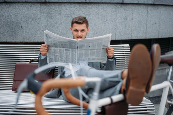 ダウンタウンのオフィスビルのベンチで自転車で新聞を読んでいるビジネスマン 街の通り 都市のスタイルでエコ輸送に乗るビジネス人 — ストック写真