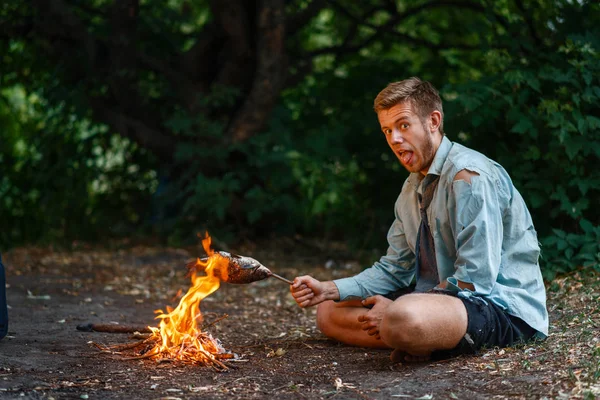 Alone office worker warms by the fire on desert island. Business risk, collapse or bankruptcy concept