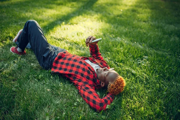 Чорний Студент Телефоном Лежить Траві Літньому Парку Підліток Навчається Відпочиває — стокове фото