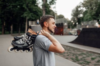 Paten kayan, erkek patenci omuzunda paten taşıyan, arka görüşlü. Şehir pateni, açık havada aktif ekstrem spor, gençlik keyfi, paten