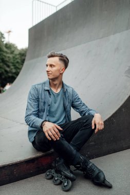 Paten kayarken, erkek kaykaycı rampada poz verir. Şehir pateni, açık havada aktif ekstrem spor, gençlik keyfi, paten