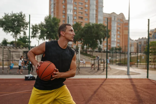 篮球运动员准备在室外场地上投篮 身穿运动服的男子运动员在街头篮球训练中持球 — 图库照片