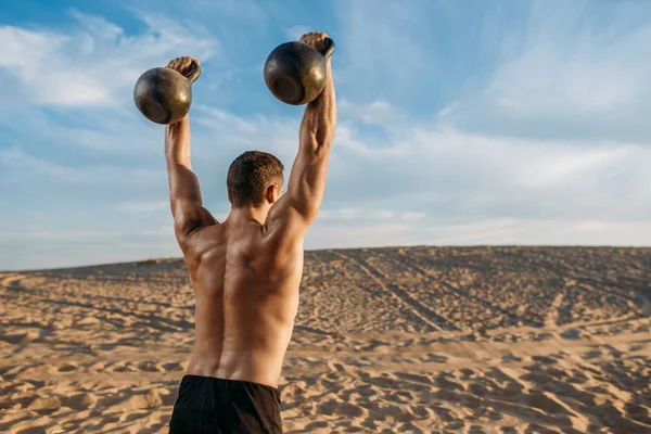 Atleta Masculino Fazendo Exercícios Com Dois Kettlebell Deserto Dia Ensolarado — Fotografia de Stock