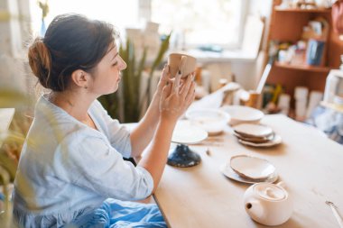 Kadın çömlekçi tenceresi parmaklarıyla, çömlek atölyesiyle. Kâse kalıbı çıkaran bir kadın. El yapımı seramik sanat, kilden sofra takımı