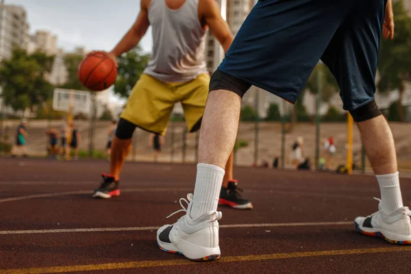 Basketbol sahasının ortasında açık sahada iki oyuncu. Spor giyim sektöründe erkek sporcular sokak topu antrenmanında oynuyor.