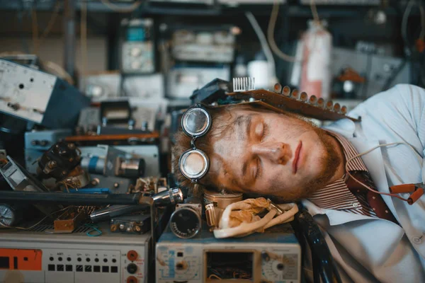 研究室の装置で寝てる奇妙なエンジニアバックグラウンドでの電気試験ツール 研究室設備 工学ワークショップ — ストック写真
