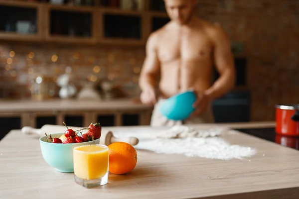 Nude man cooking dessert on the kitchen. Naked male person preparing breakfast at home, food preparation without clothes