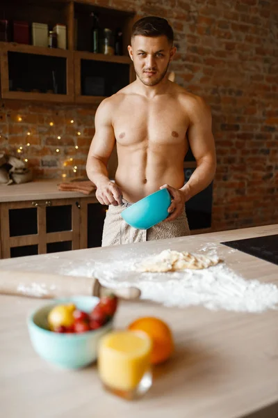 Nude man cooking dessert on the kitchen. Naked male person preparing breakfast at home, food preparation