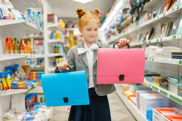 Little school girl with two bags in stationery store. Female child buying office supplies in shop, schoolchild in supermarket