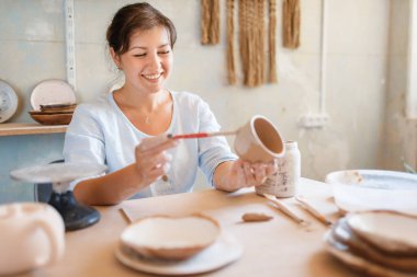 Kadın çömlekçi tencere boyuyor, çömlek atölyesi. Kâse kalıbı çıkaran bir kadın. El yapımı seramik sanat, kilden sofra takımı