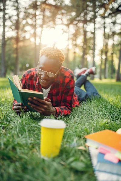 Studente Africano Cuffia Sdraiato Sull Erba Leggere Libro Nel Parco — Foto Stock