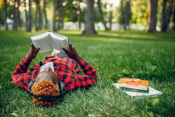 Afrykański Student Słuchawkach Spoczywa Trawie Letnim Parku — Zdjęcie stockowe