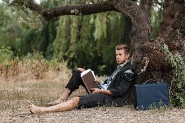 Yırtık takım elbiseli yalnız iş adamı kayıp adada yerde oturuyor. İş riski, çöküş veya iflas kavramı