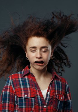 Kadının yüzüne güçlü bir rüzgar esiyor, komik bir duygu. Güçlü hava akışı kadın üzerinde, siyah arka planda.