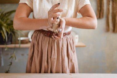 Kadın usta kil yoğurur, çömlek atölyesi. Çalışan kadın kalıpları. El yapımı seramik sanat, sofra takımı yapımı.