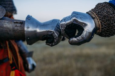 Ortaçağ şövalyeleri elleri metal eldivenlerle yakın çekim, büyük turnuva. Zırhlı eski bir savaşçı tarlada poz veriyor.