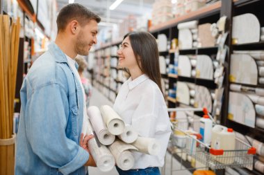 Hırdavatçıda duvar örmeyi seçen genç bir çift. Erkek ve kadın müşteriler mağazadaki mallara bakarlar.