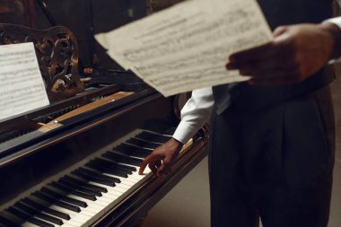 Sahnede elinde müzik defteri olan Afrikalı bir piyanist. Arka planda spot ışıkları var.