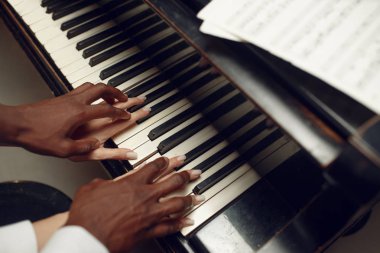 Afrikalı piyanist tuşlara basıyor, klasik müzik çalıyor.