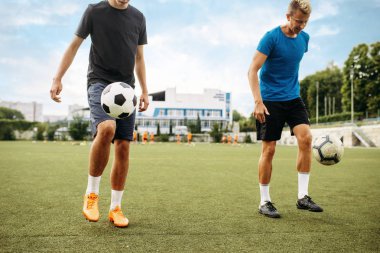 Erkek futbolcular sahada toplarla antrenman yapıyor. Dışarıdaki stadyumda futbolcular, maçtan önce takım çalışması. 