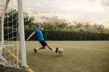 Erkek futbolcu topa vurur ve kapıyı kurtarır. Açık stadyumdaki futbolcu, maçtan önce antrenman, futbol antrenmanı.