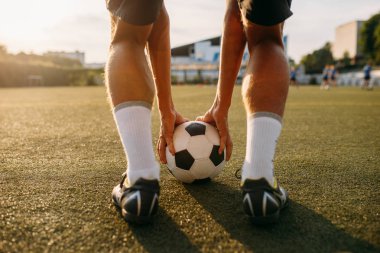 Erkek futbolcu sahada topa vurmaya hazırlanıyor. Güneşli bir günde stadyumda futbolcu, maçtan önce antrenman, futbol antrenmanı.
