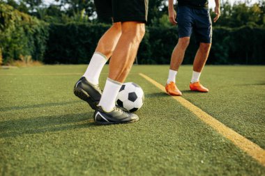 Erkek futbolcular sahada topla oynuyorlar. Açık stadyumdaki futbolcu, futbol maçından önce antrenman yapıyor.