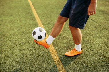 Top sahanın üzerinde duran erkek futbolcu. Açık stadyumdaki futbolcu, futbol maçından önce antrenman yapıyor.
