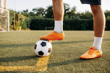 Erkek futbolcu bacakları sahada ayakta duruyor. Açık stadyumdaki futbolcu, futbol maçından önce antrenman yapıyor.