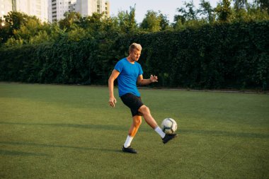 Top sahanın üzerinde duran erkek futbolcu. Açık stadyumdaki futbolcu, futbol maçından önce antrenman yapıyor.